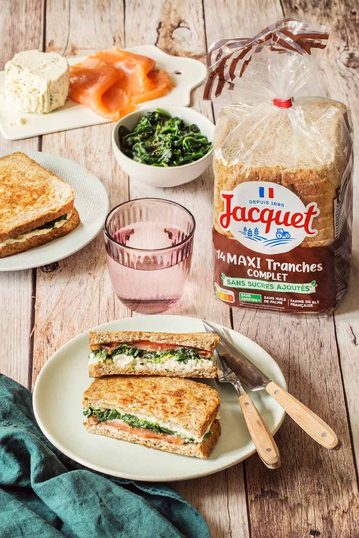Agence Belle Nouvelle ! Photo d'une table prise en hauteur avec une assiette et un sandwich, un verre, un bol de salade, un paquet de pain de mie Maxi Tranche Complet Jacquet