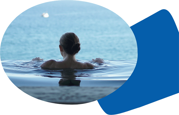 Agence Belle Nouvelle ! Photo d'une femme de dos immergée jusqu'aux épaules dans une piscine face à la mer