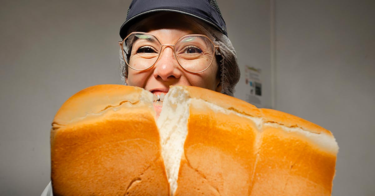 Agence Belle Nouvelle ! Photo pour Jacquet d'une femme souriante tenant un pain coupé entre ses mains