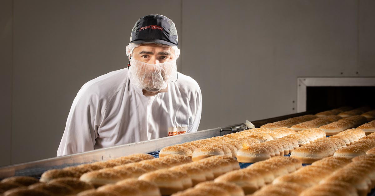 Agence Belle Nouvelle ! Photo pour Jacquet d'un homme devant un ligne de production de pain hamburger